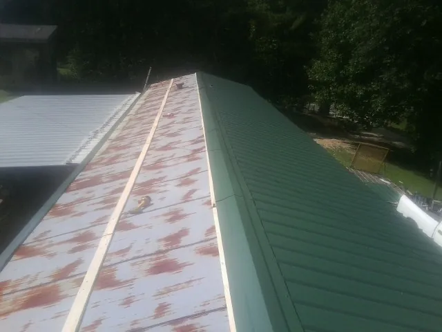 Old rusted panels beside newly installed green metal roofing — Wind Damage Roof Repair by Roofing Brothers in Deltona