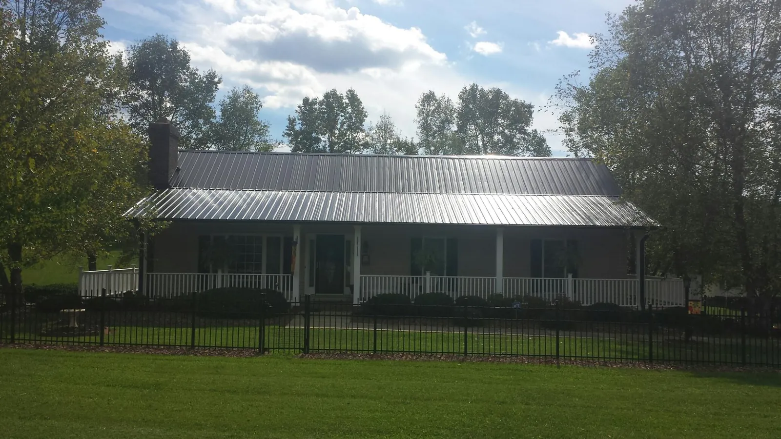Gray metal roof on a brick ranch with a full width front porch — Gutter Guard Installation work by our crew in Deltona