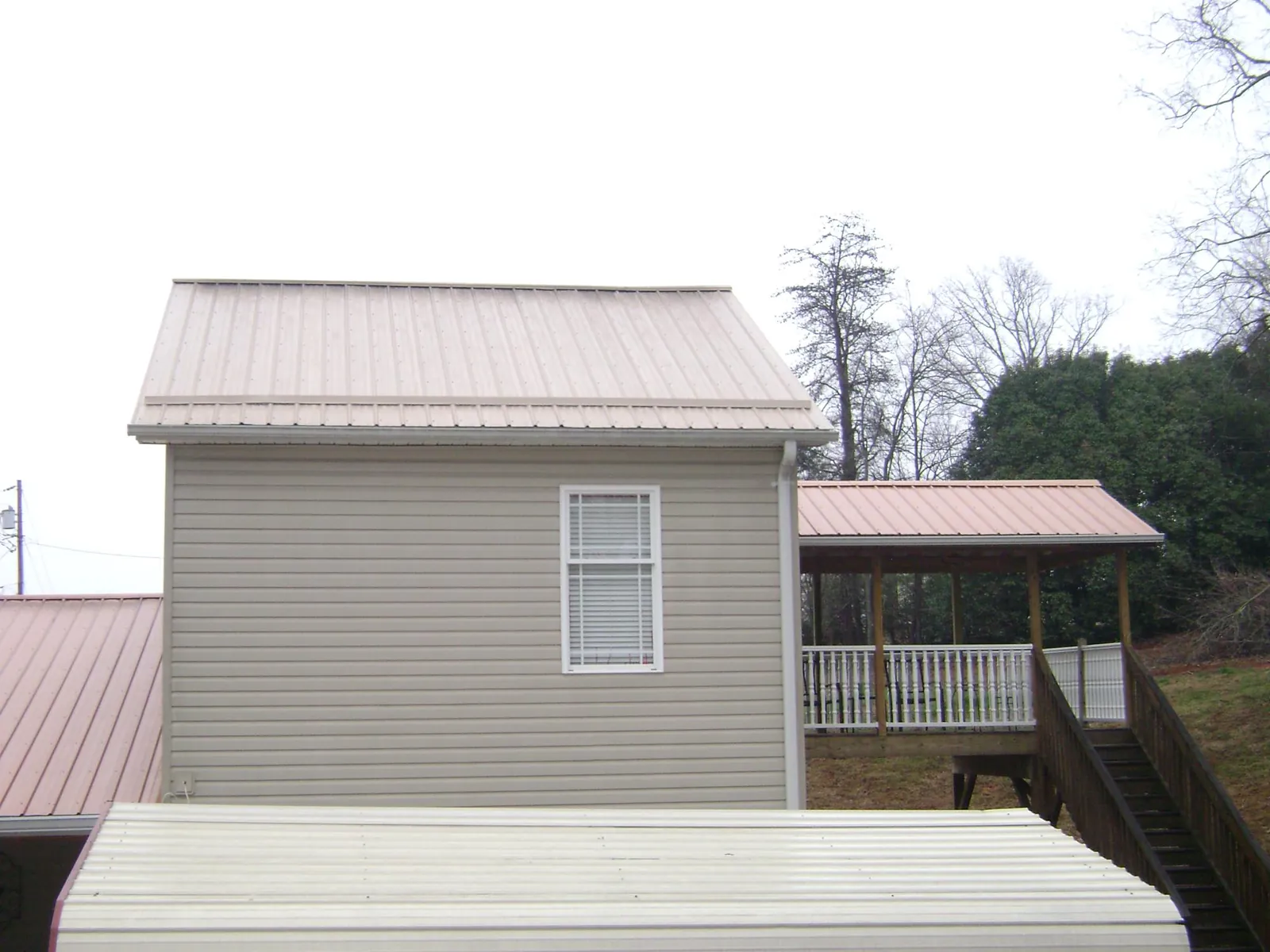 Tan metal roofs on a two story addition and attached porch, from a Roof Replacement job in Deltona