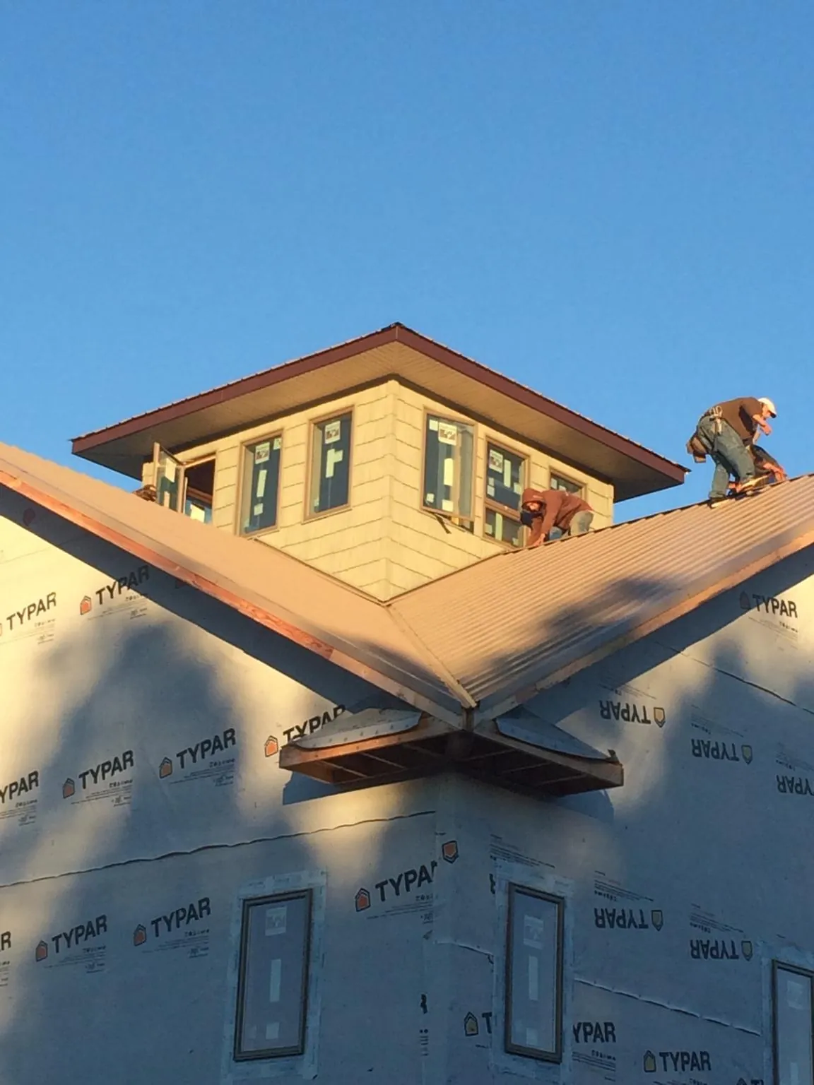Roofers working around a rooftop cupola on a new metal roof at sunset — Roof Waterproofing in Deltona by Roofing Brothers